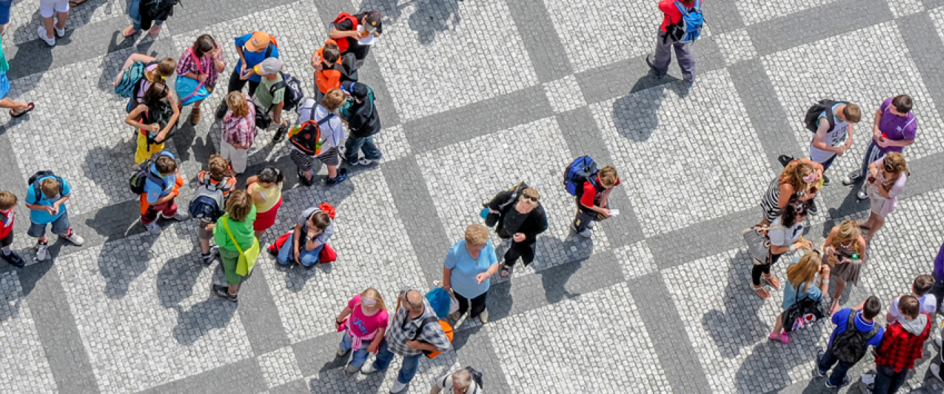 Different groups of people gather together on a paved, gridded square.